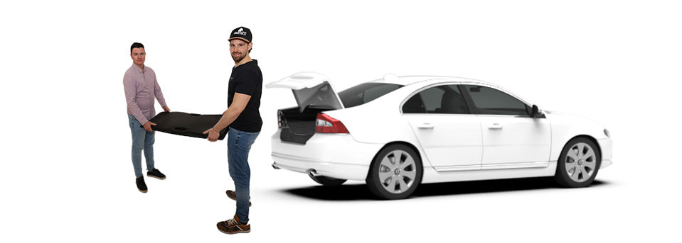 zwei Personen heben eine Auffahrrampe in den Kofferraum eines Autos